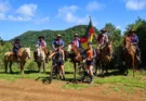 Grupo de tropeiros renascentes a cavalo e cicloturistas contemporâneos no Costão do Cambará, Campos de Cima da Serra (RS), com bandeira histórica e paisagem montanhosa. Foto: Ivan Mendes © Lobi Ciclotur
